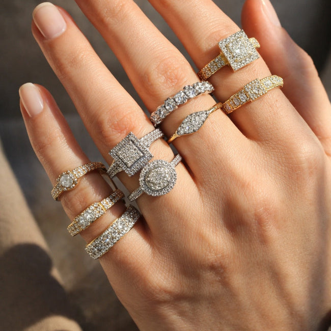 Hand wearing multiple diamond rings with a blurred background