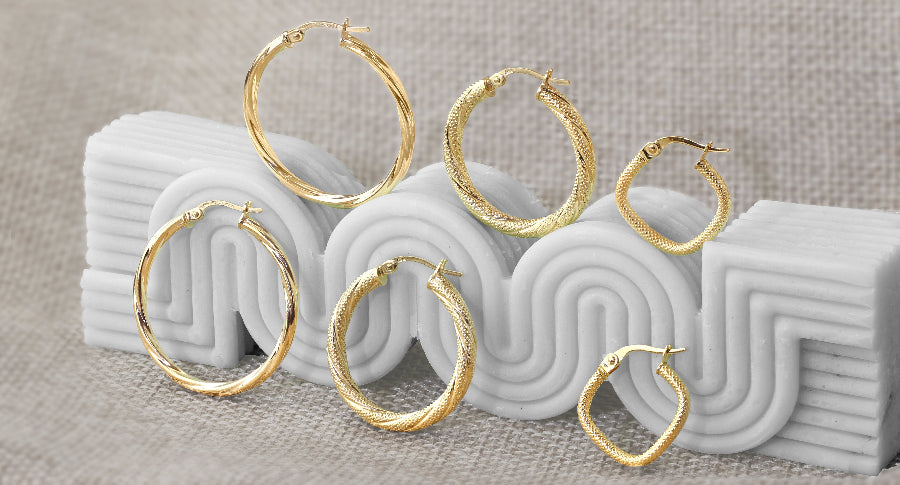 Set of gold hoop earrings on a textured surface